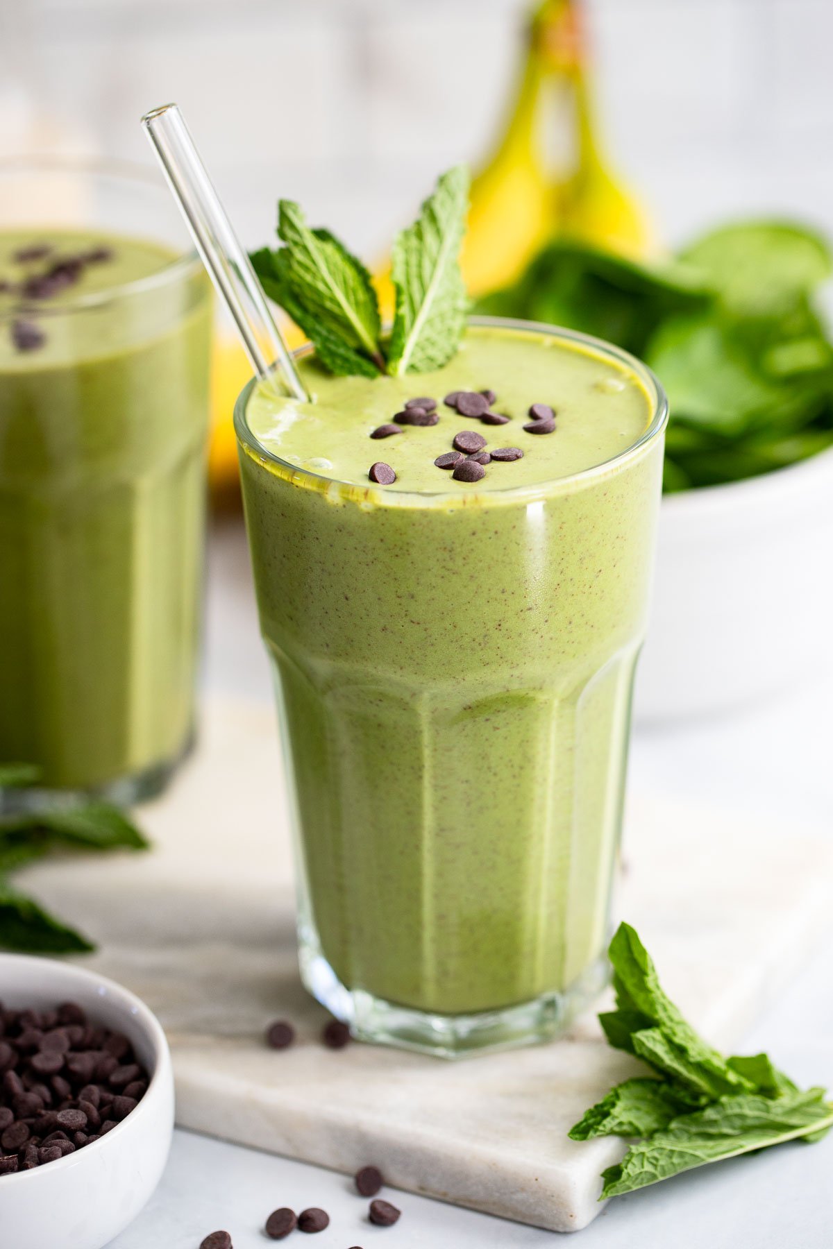 mint smoothie in a tall glass garnished with fresh mint.