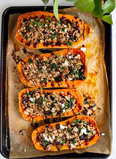 assembled stuffed butternut squash lined up on a baking sheet.
