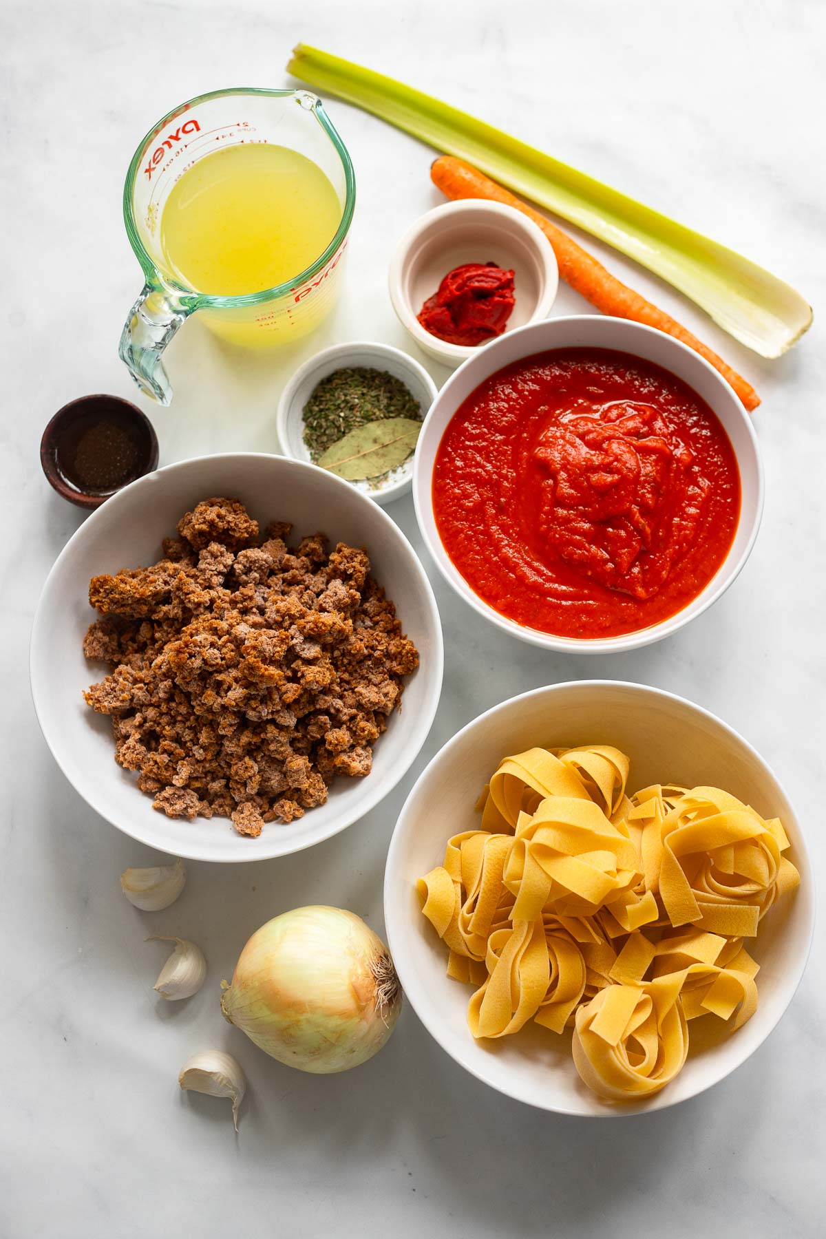ingredients for vegetarian bolognese in white bowls on a white background. 