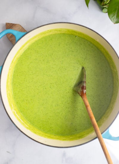 pureed creamy celery soup in a large dutch oven with a wooden spoon.