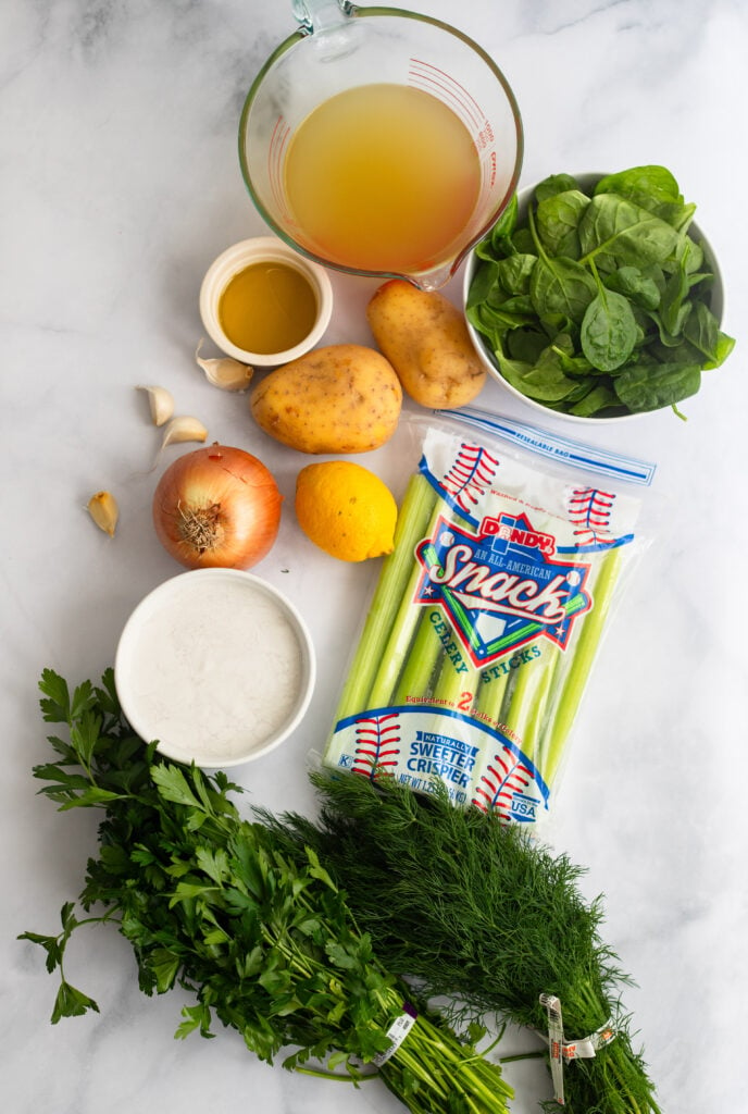 creamy celery soup ingredients laid out on a white marble background. 