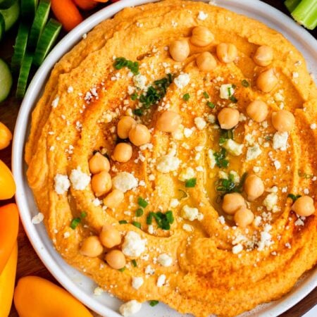 buffalo hummus on a plate garnished with blue cheese and chives.