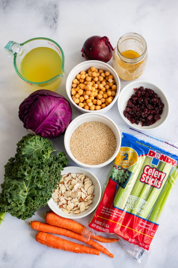 quinoa and kale salad (Costco copycat) ingredients in white bowls on a marble background. 