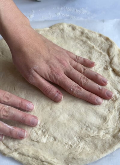shaping pizza dough into a a crust.