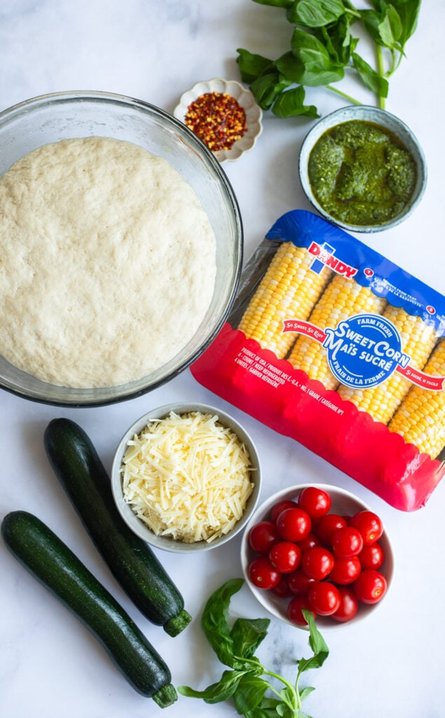 sweet corn pizza ingredients in small bowls on a white background. 