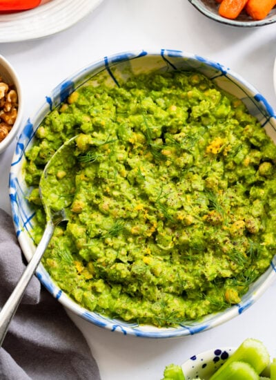 green goddess chickpea salad in a blue bowl with a serving spoon.