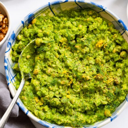 green goddess chickpea salad in a blue bowl with a serving spoon.