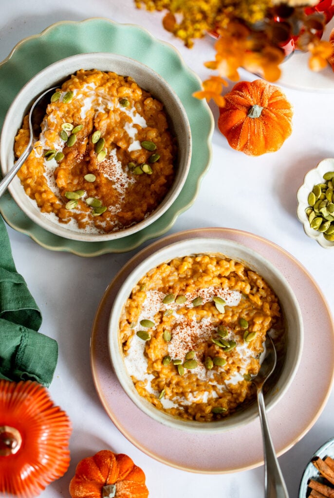 2 bowls of pumpkin spice rice pudding topped with pumpkin seeds. 