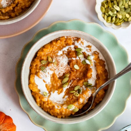 pumpkin spice rice pudding in a bowl topped with pumpkin seeds