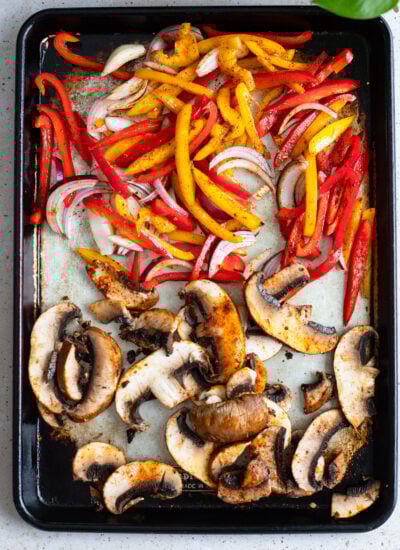 peppers, onion, and mushroom on a sheet pan ready to bake