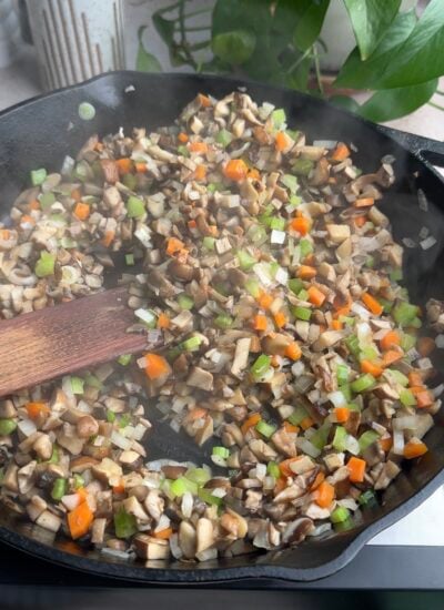 mushrooms and veggies sautéing in a cast iron skillet.