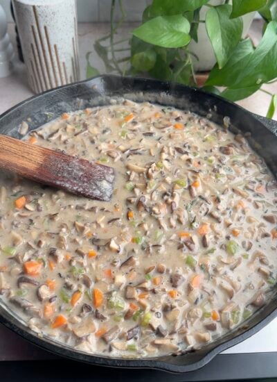mushrooms and vegetables in a gravy in a cast iron skillet. 