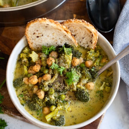 creamy broccoli and chickpeas in a bowl with a slice of sourdough.