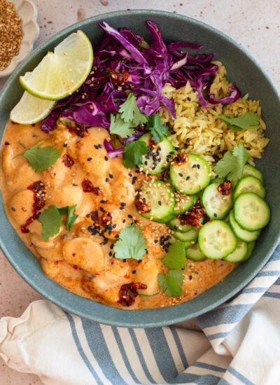 peanut sauce butter beans in a bowl with rice, cucumbers. and purple cabbage
