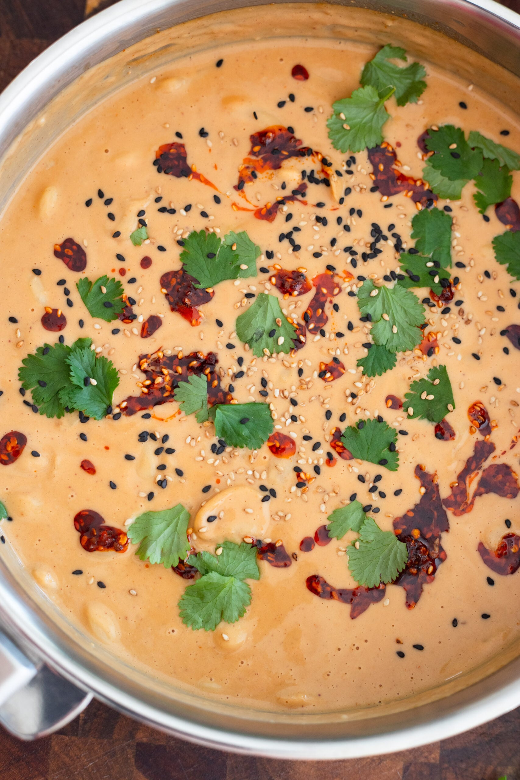 peanut sauce butter beans in a skillet garnished with cilantro and chili crisp