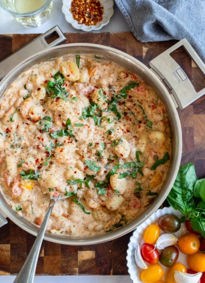 creamy tomato gnocchi in a skillet garnished with fresh basil