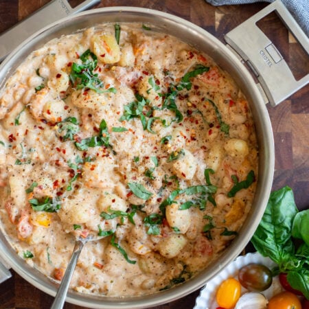 creamy tomato gnocchi in a skillet garnished with fresh basil