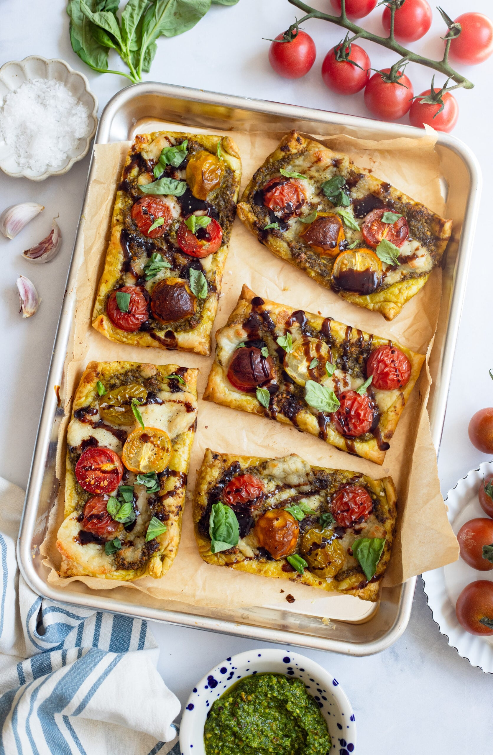 tomato basil tarts on a sheet pan with parchment paper