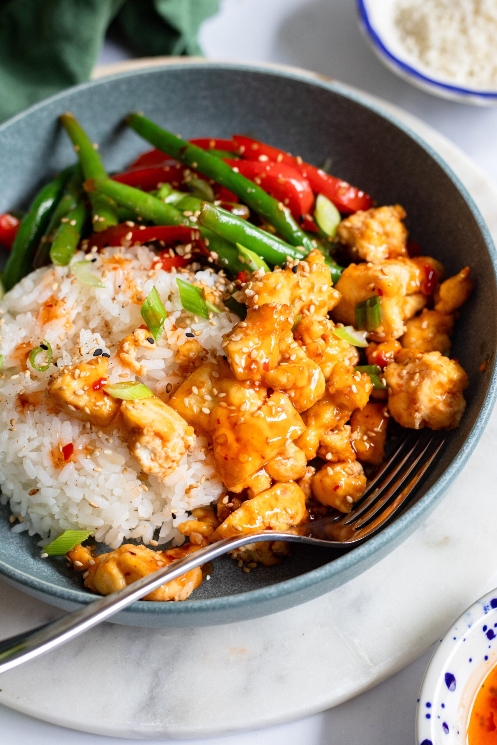sticky tofu bowl with rice and stir fried veggie stopped with sesame seeds