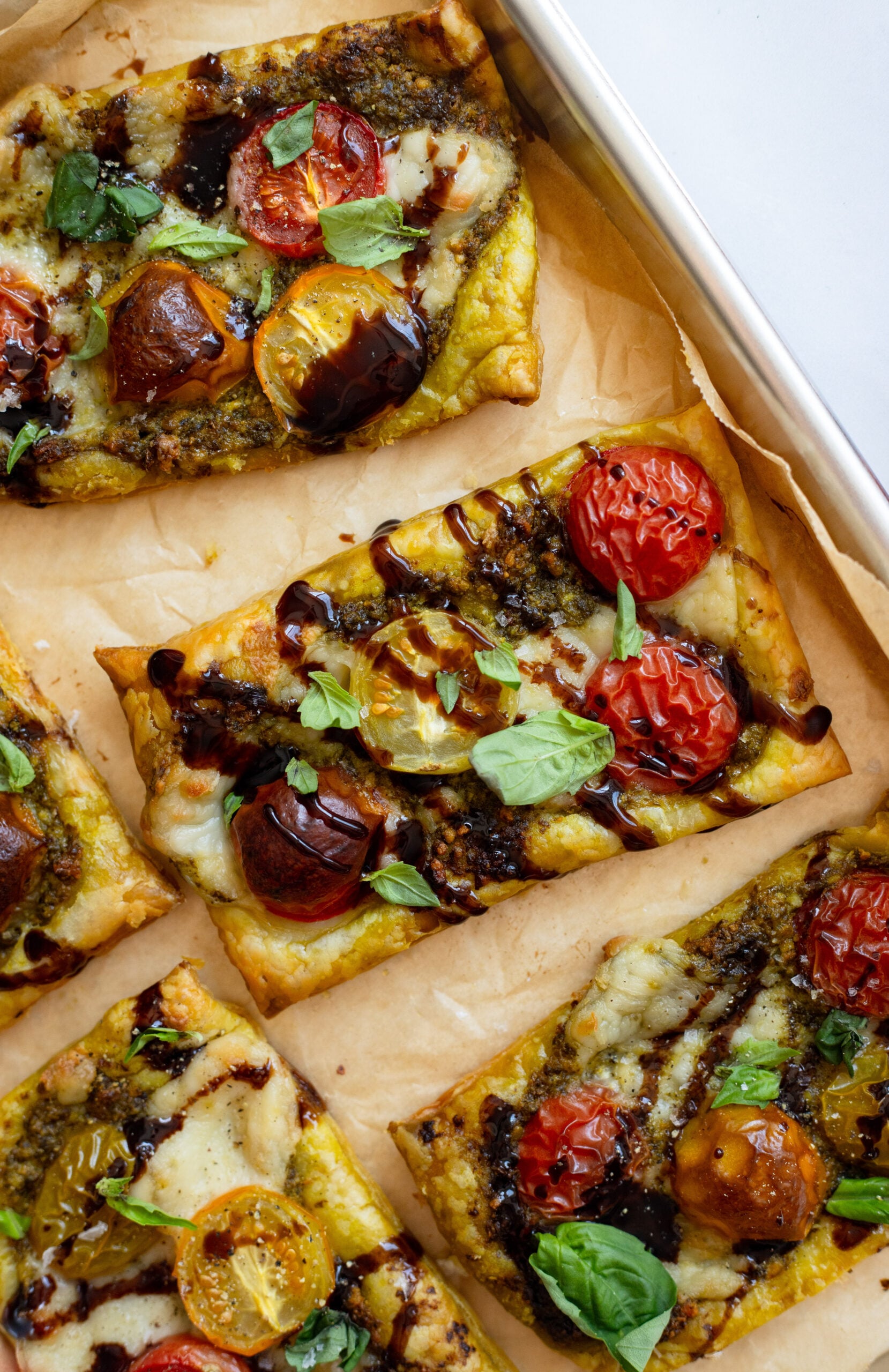 close up of a tomato tart garnished with basil on a sheet pan