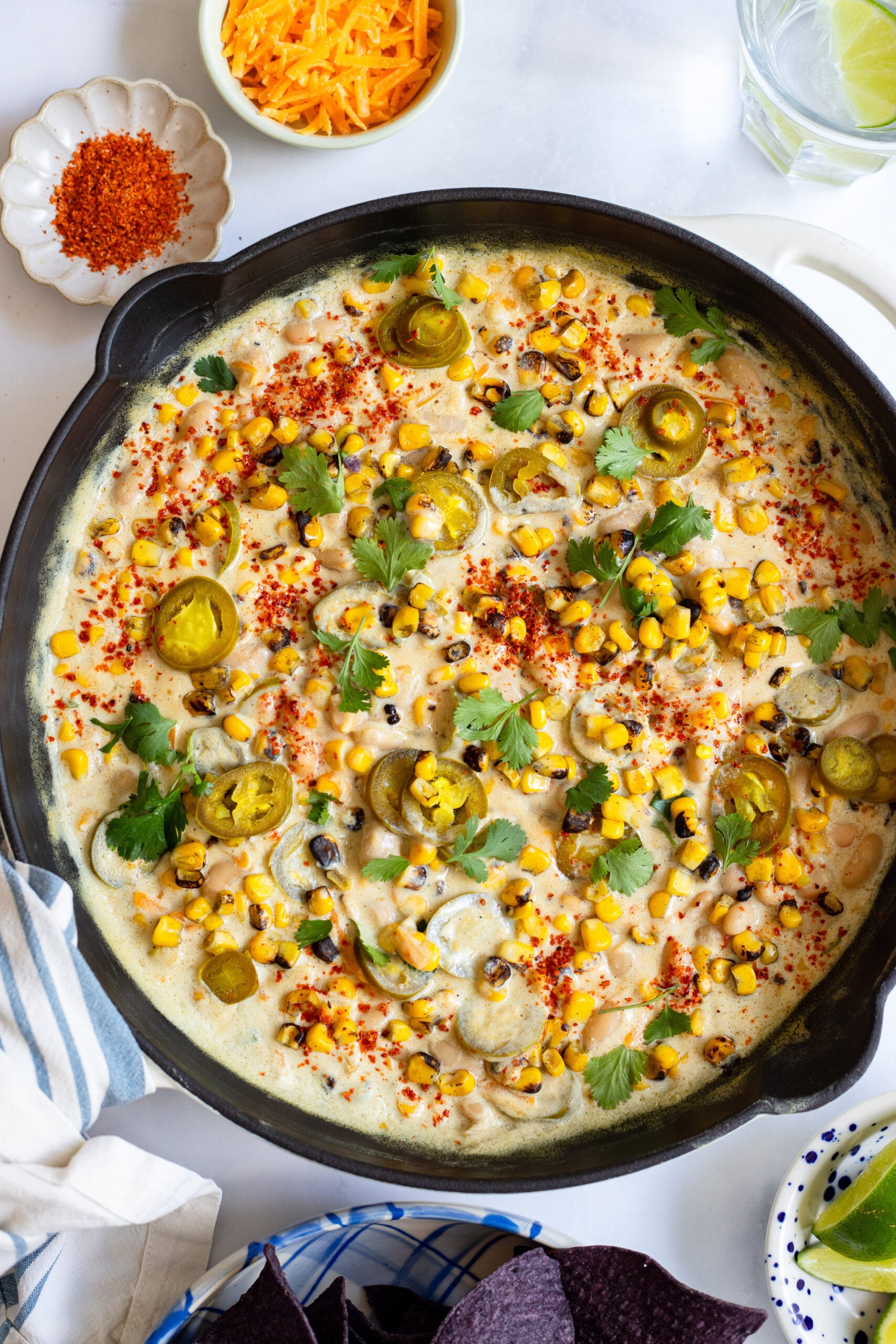 creamy jalapeno corn bean dip in a skillet garnished with pickled jalapeños