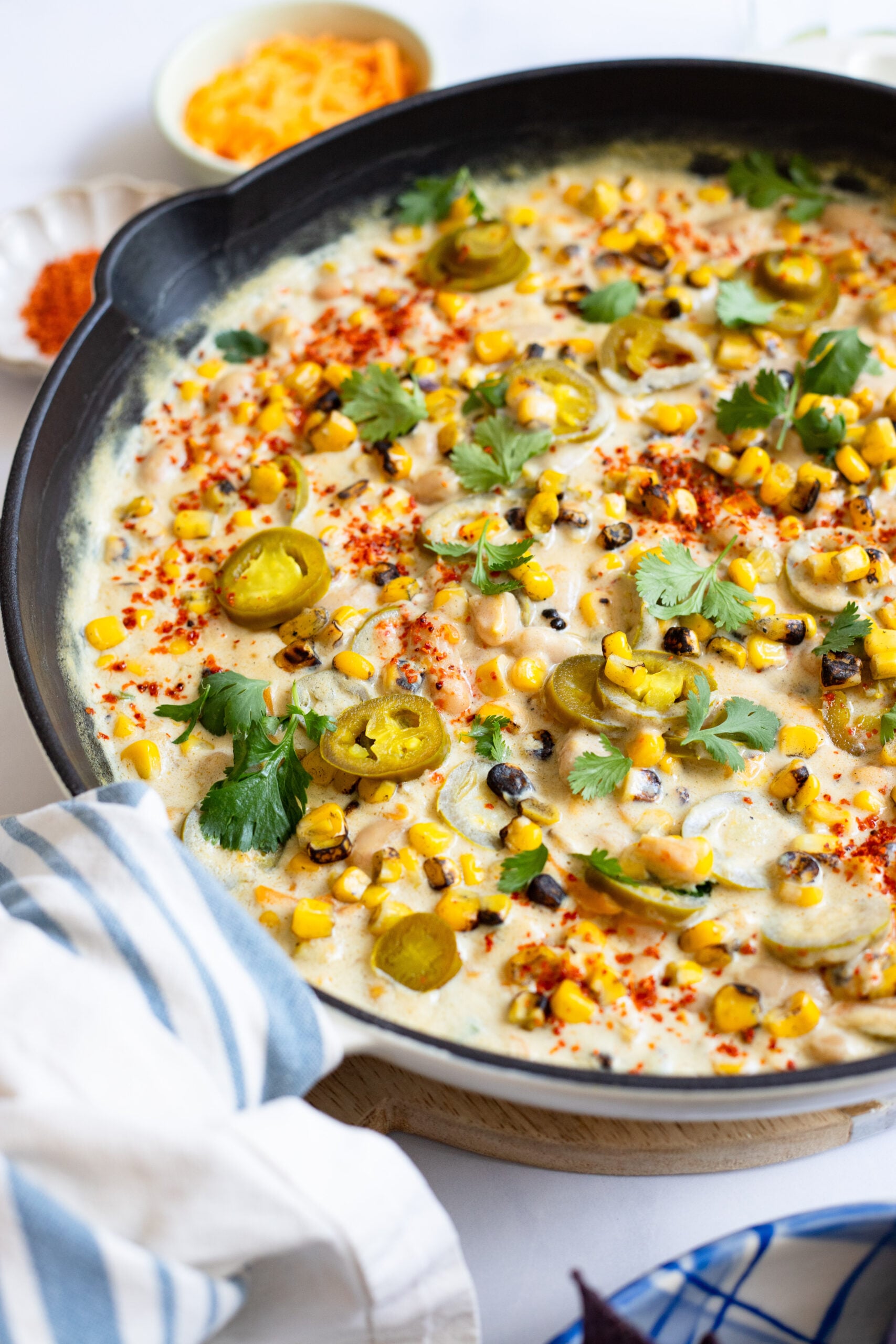 creamy corn and jalapeno bean dip in a skillet garnished with cilantro