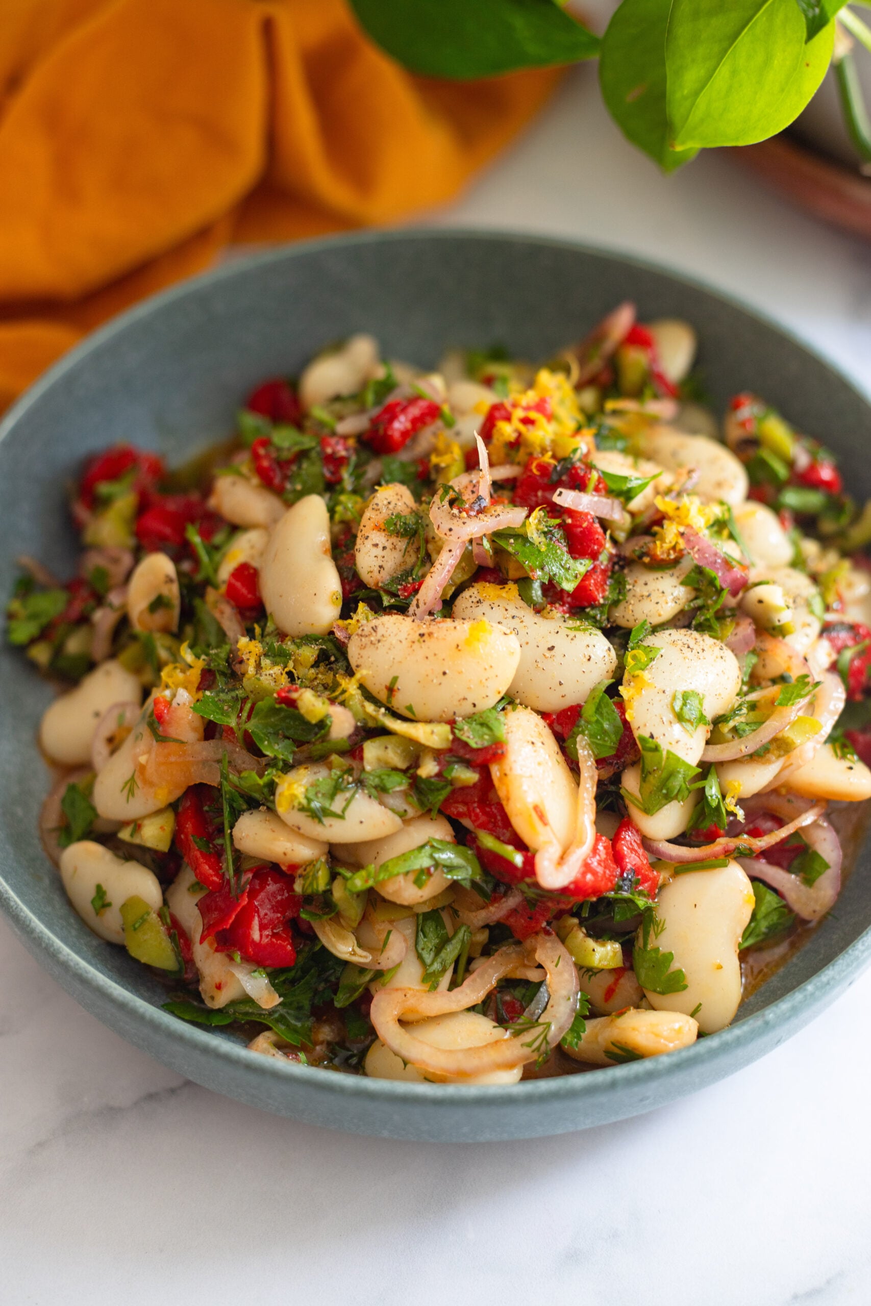 marinated butter bean salad garnished with lemon zest in a blue serving bowl