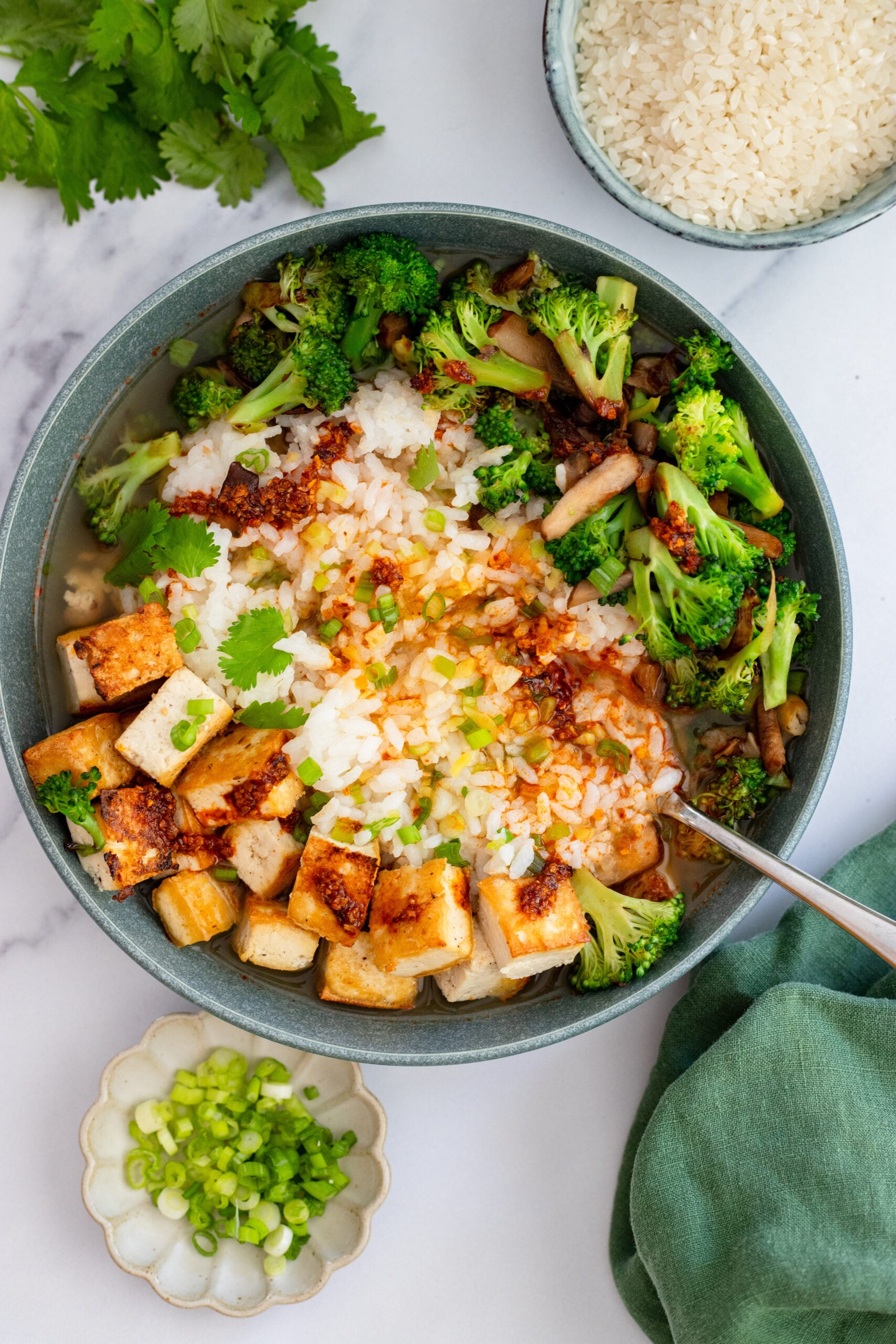 brothy rice bowl with broccoli and tofu in a blue bowl