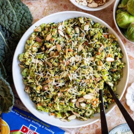 kale brussels sprouts celery slaw in a serving bowl with spoons