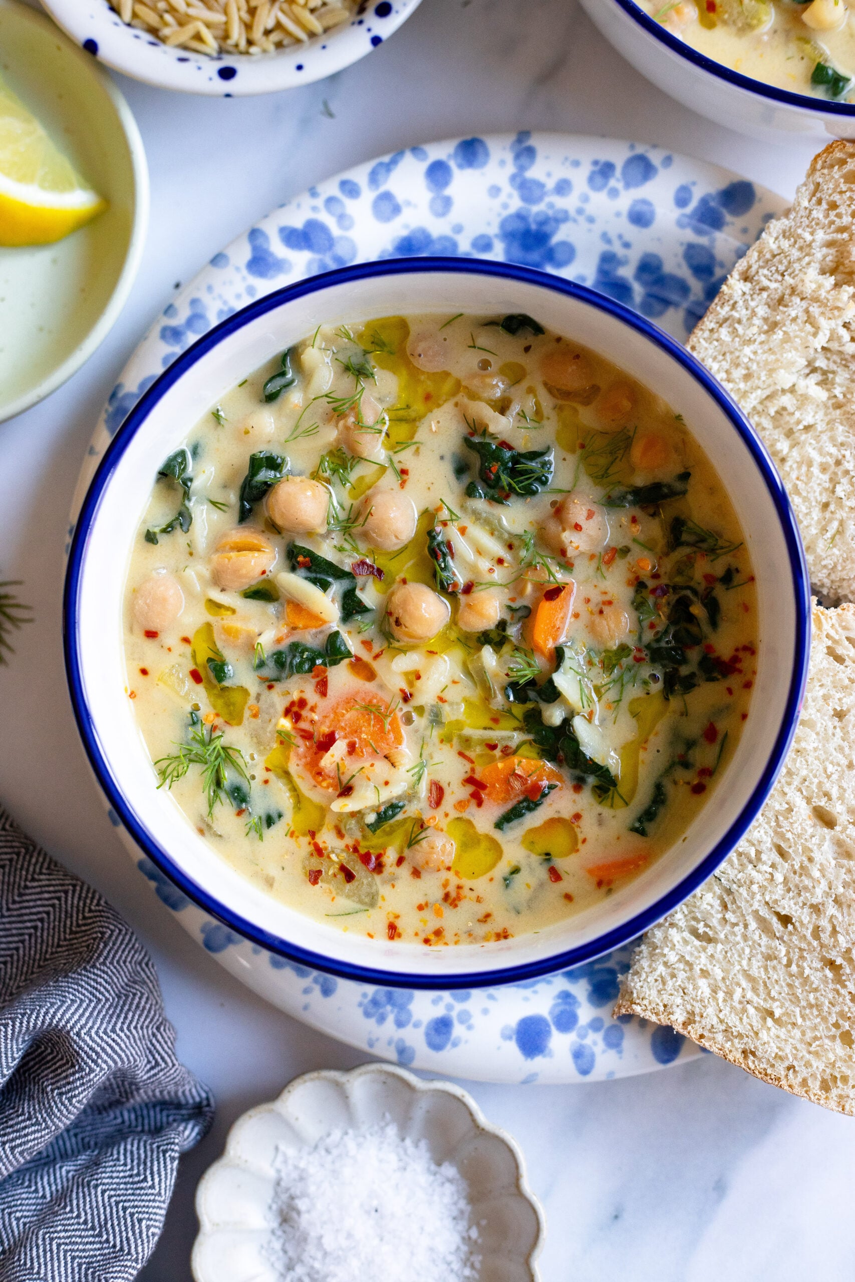 lemon chickpea orzo soup in a bowl with bread on the side